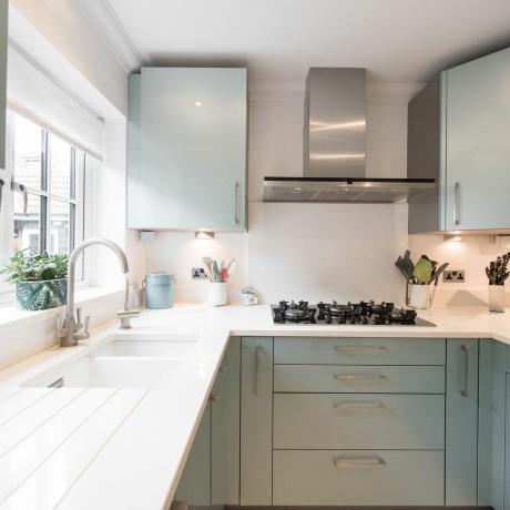bir ev içinde lavabo altı lavabolu beyaz kuvars tezgahlı modern bir metalik yeşil hazır mutfağın genel iç görünümü