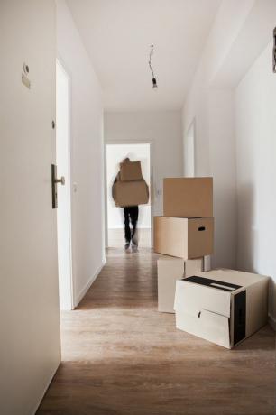 Adam boşaltma karton kutular yeni bir evin koridorunda