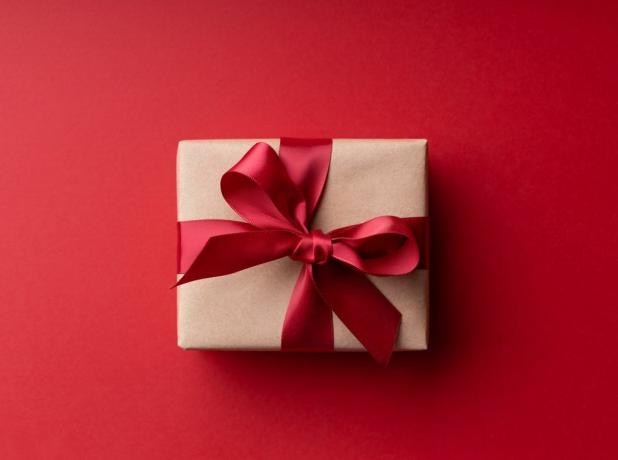 Kırmızı arka planda kırmızı fiyonklu Noel hediye kutusunun üst görünümü