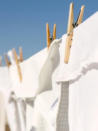 parlak sıcak güneşin arka planında bir çamaşır ipinde kurumaya asılı beyaz giysiler açık mavi bir gökyüzüdür.
