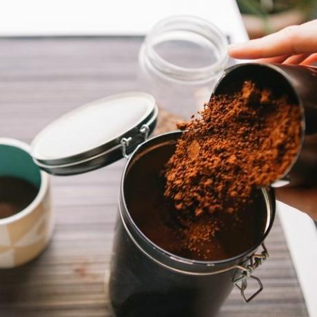 kahve telvesi bahçe kırpılmış eller öğütülmüş kahveyi yeniden kullanılabilir bir kaba döküyor