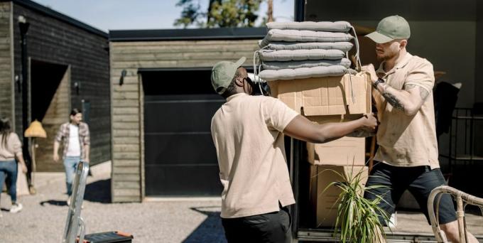 Güneşli bir günde kamyondan karton kutu toplayan teslimatçılar