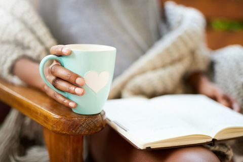 Bir kadın bir kitap ve bir fincan kahve ile rahatlatıcı kadeh kırpılmış