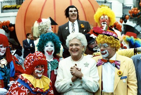Bu fotoğraf, kostümlü sanatçılarla, bir grupla poz verirken sırıtan First Lady Barbara Bush'a ait. Cadılar Bayramı'nın bir parçası olarak beyaz sarayın güney arazisinde palyaçolar ve yalnız bir kurt adam. kutlama